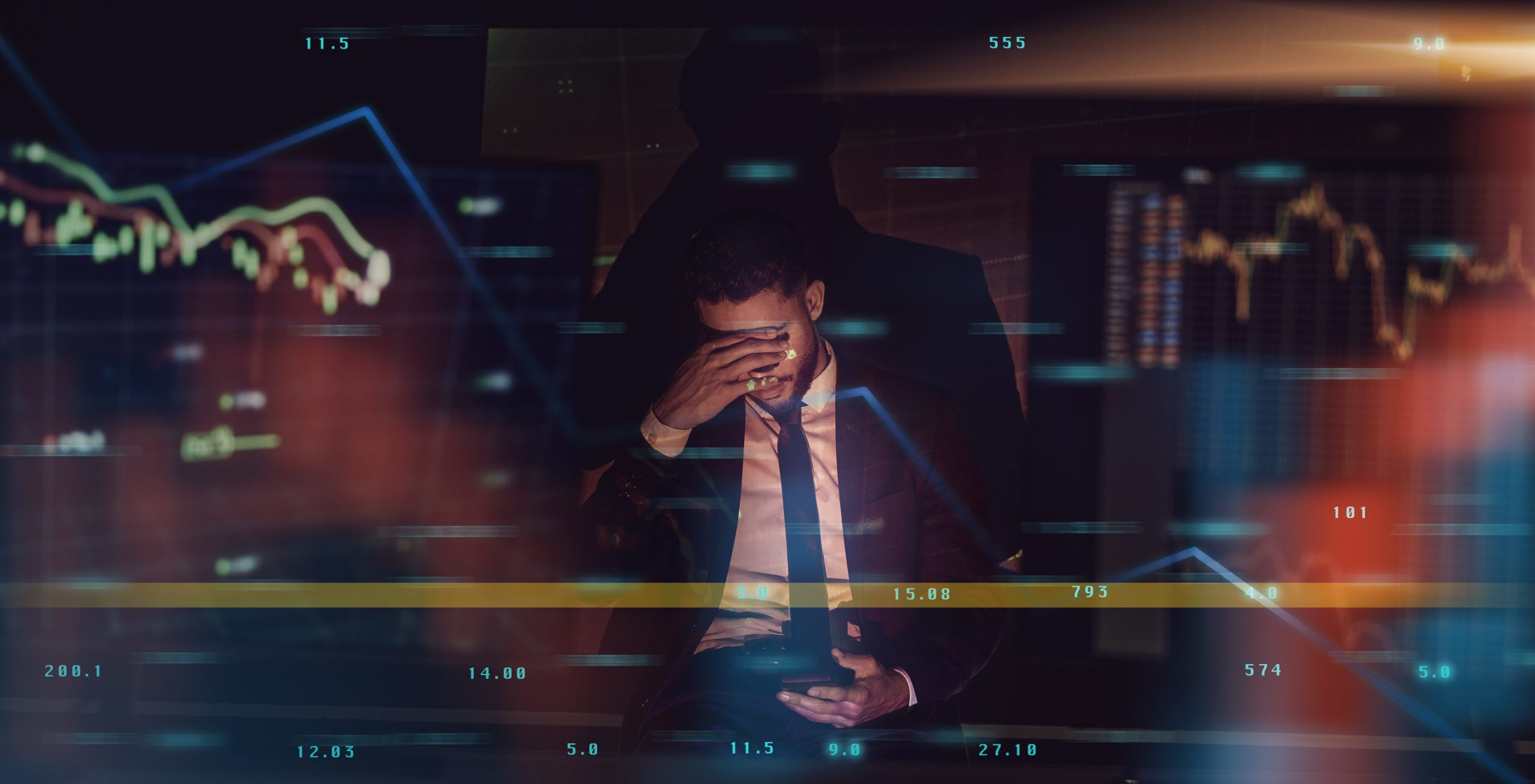 I just got the worst news. a young male trader experiencing a headache while using his smartphone to check the markets.